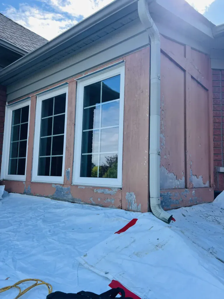 Before: peeling stucco and exposed patches on a bump-out wall above a roof