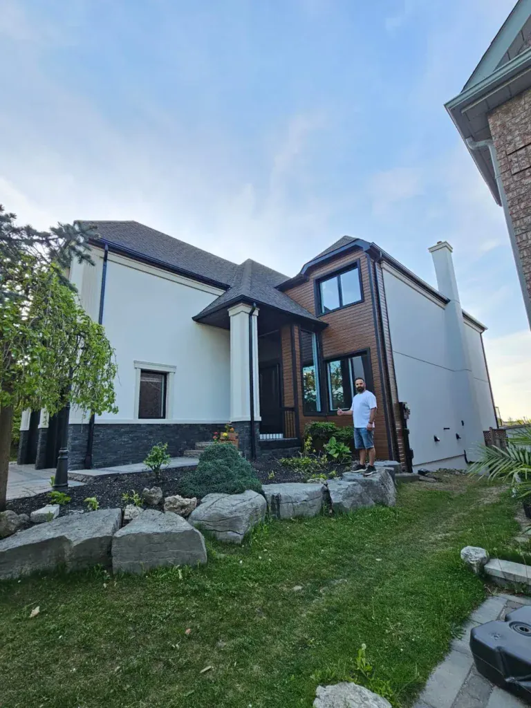 Finished white stucco exterior on a detached home with a stone-landscaped front yard