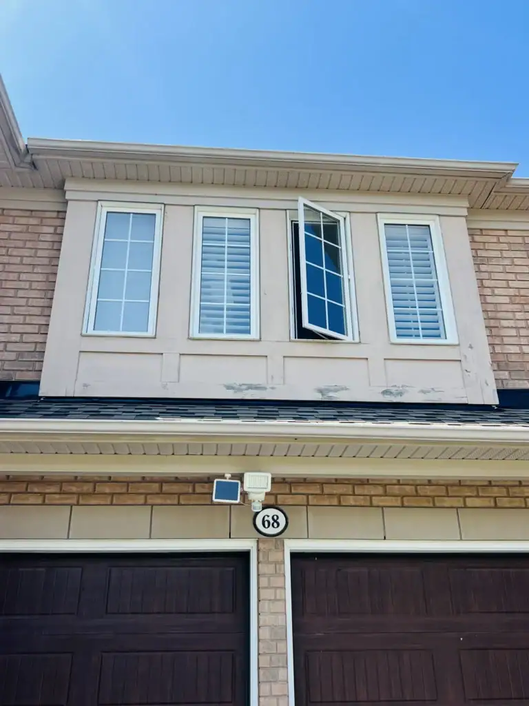 Before: peeling and cracked stucco band under upper windows above a double garage