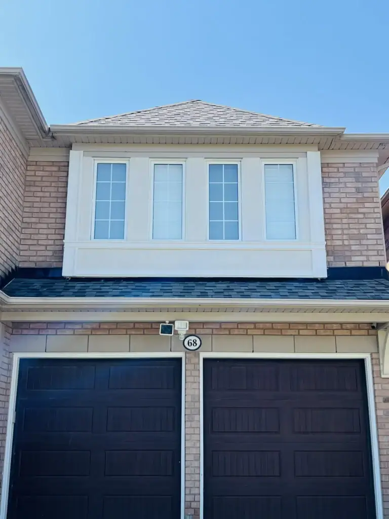 After: refinished stucco band under upper windows above a double garage